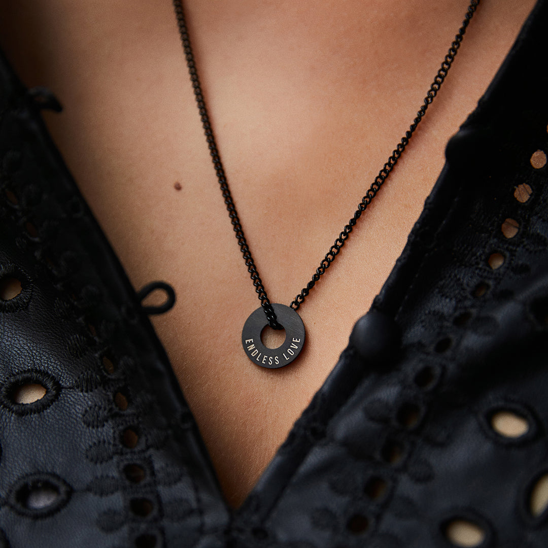 Collar Botany negro con Anilla® grabada sobre una blusa oscura