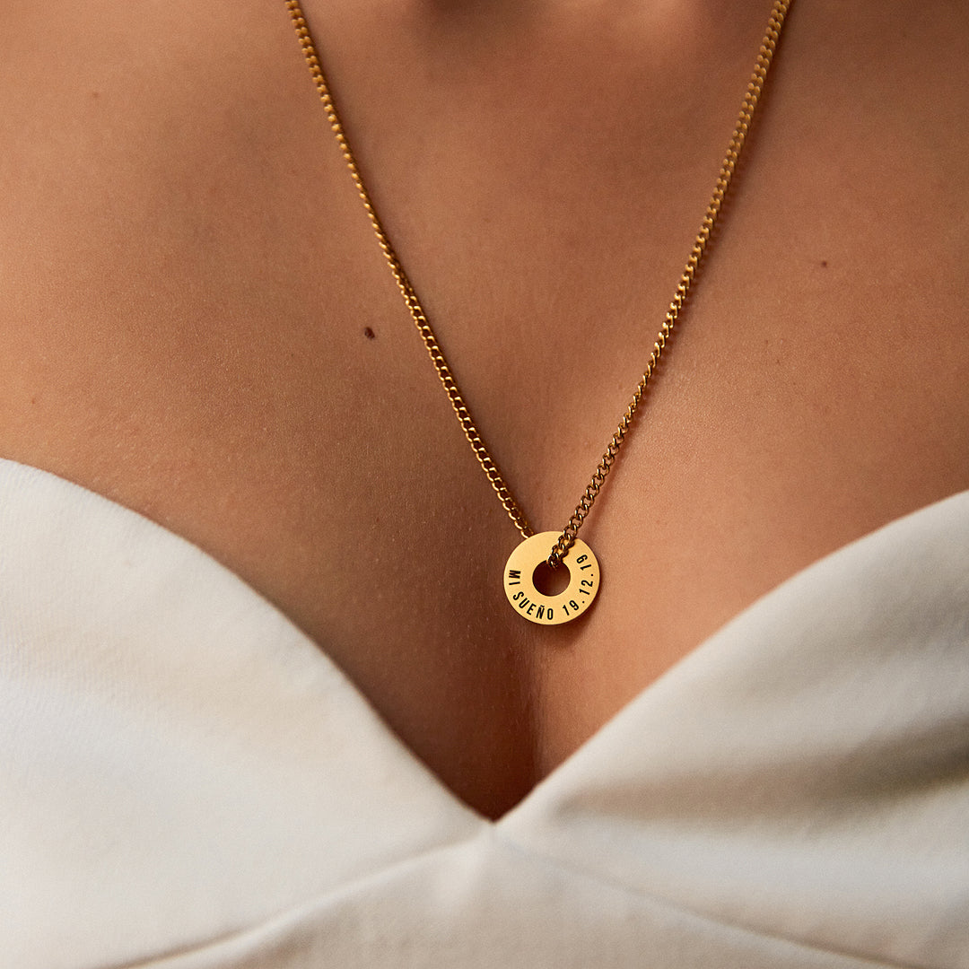 Collar Botany dorado con Anilla® grabada sobre un top blanco