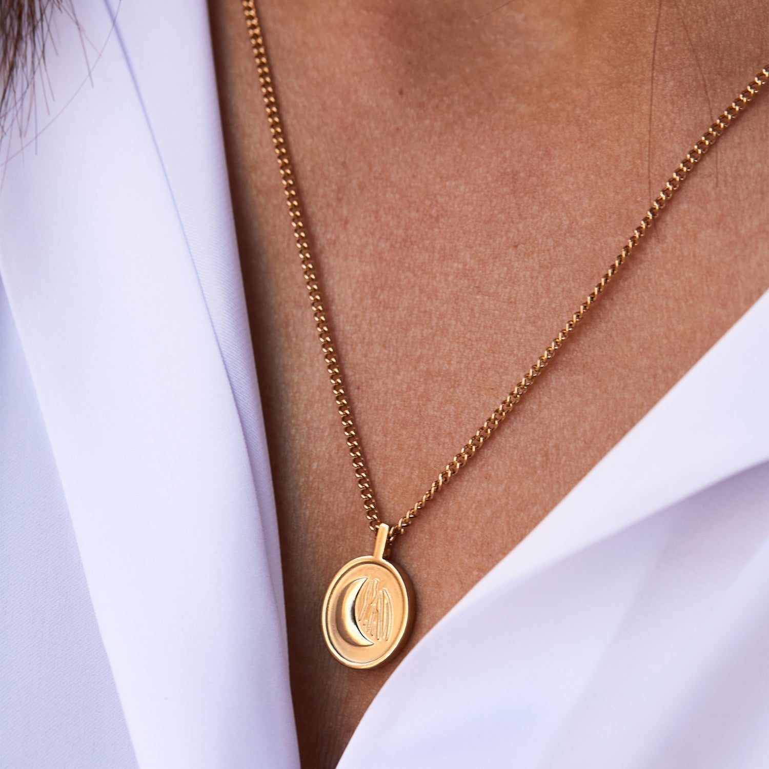 Collar Sentinel® dorado con medalla de luna llevado sobre una camisa blanca
