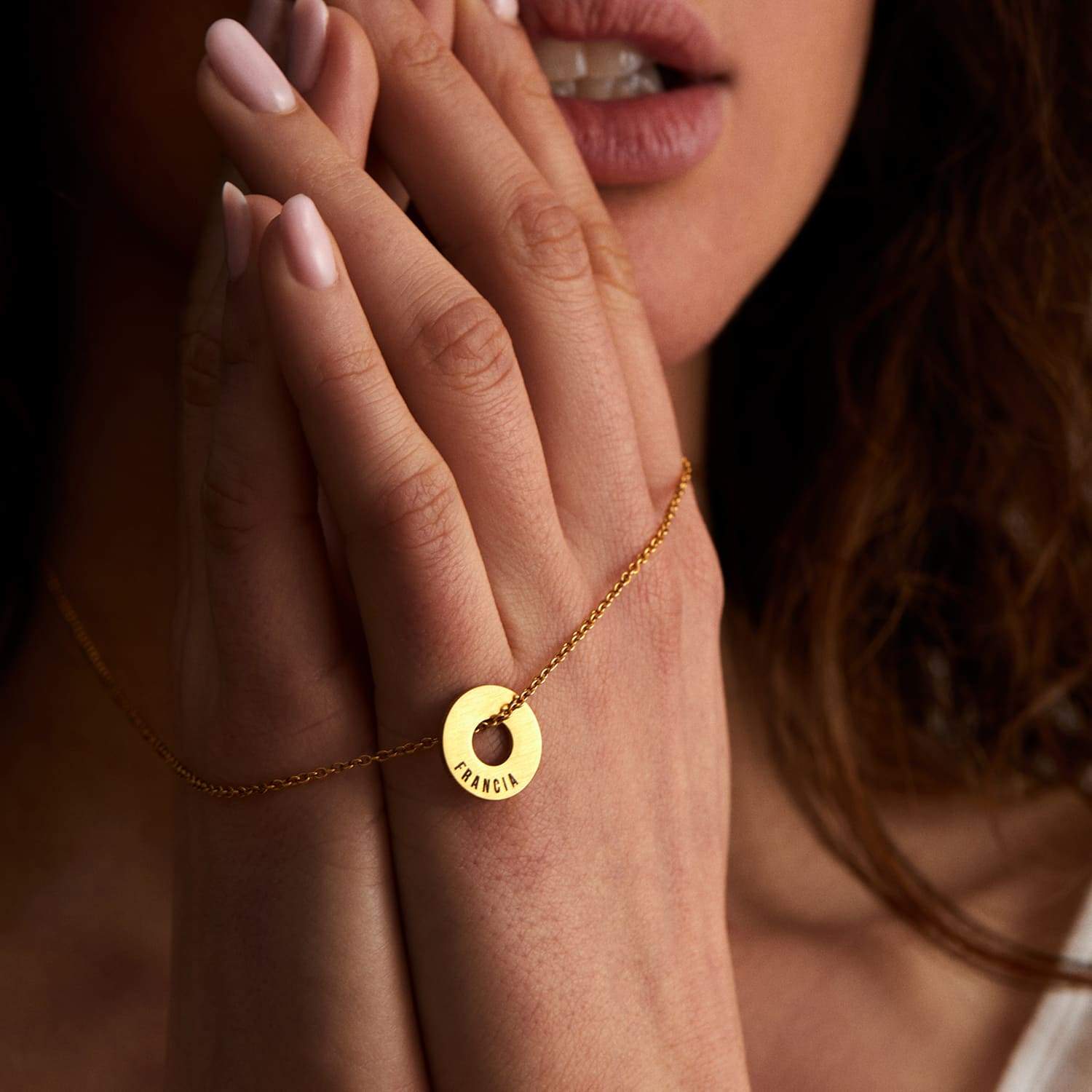 Collar Evora dorado con Anilla® grabada, con las manos juntas al pecho
