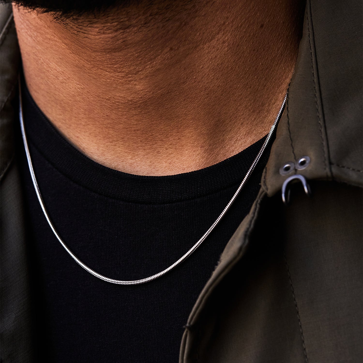 Collar Boa® en acero llevado con camiseta negra y chaqueta caqui