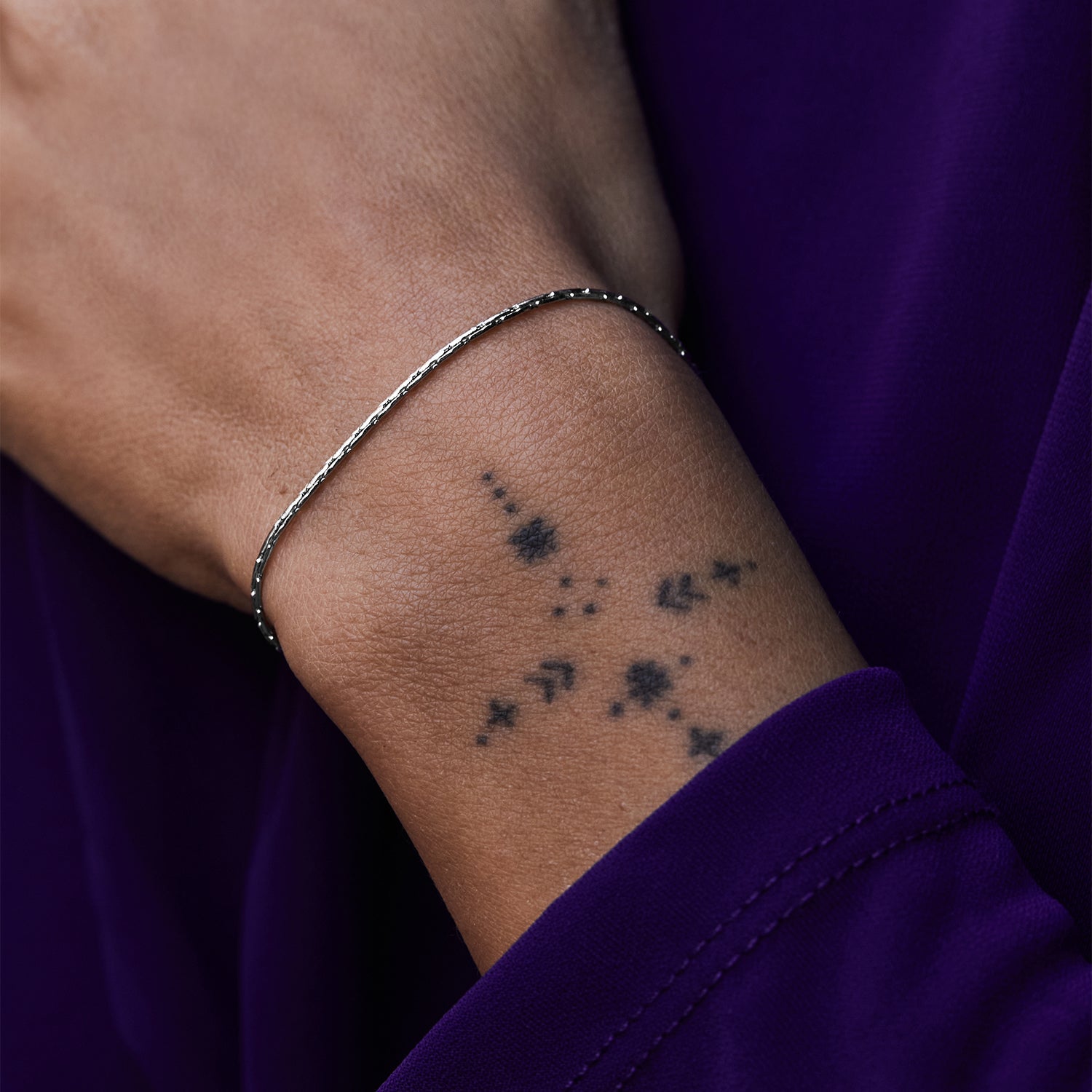 Pulsera Mamba® en acero en la muñeca sobre una manga morada