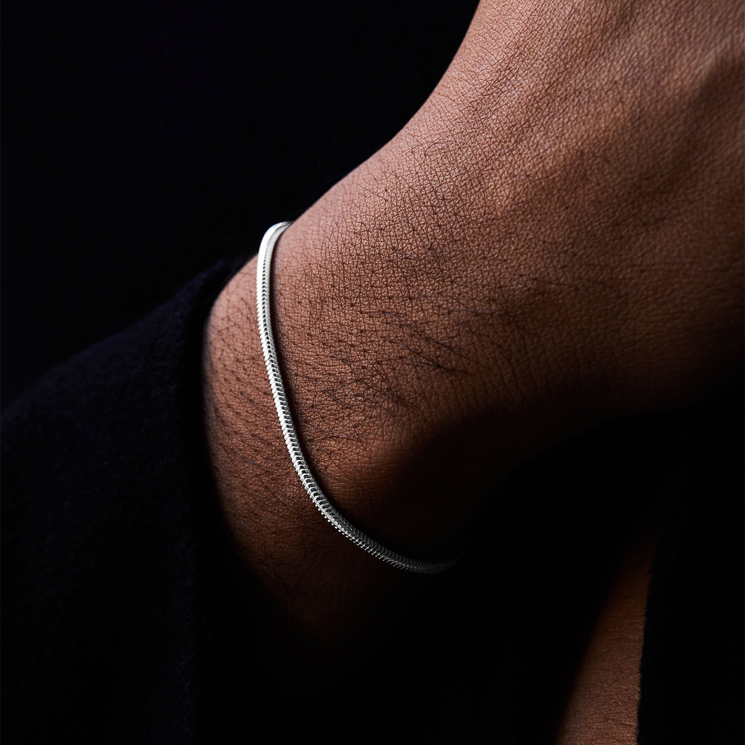 Pulsera Royal Boa® en plata de ley en la muñeca sobre fondo oscuro