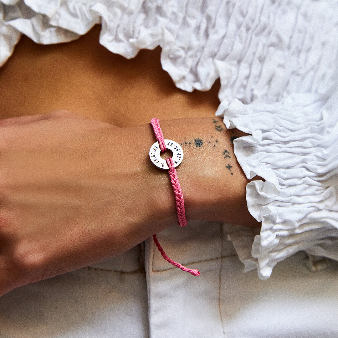Pulsera MyWord® rosa con anilla grabada en la muñeca, sobre blusa blanca