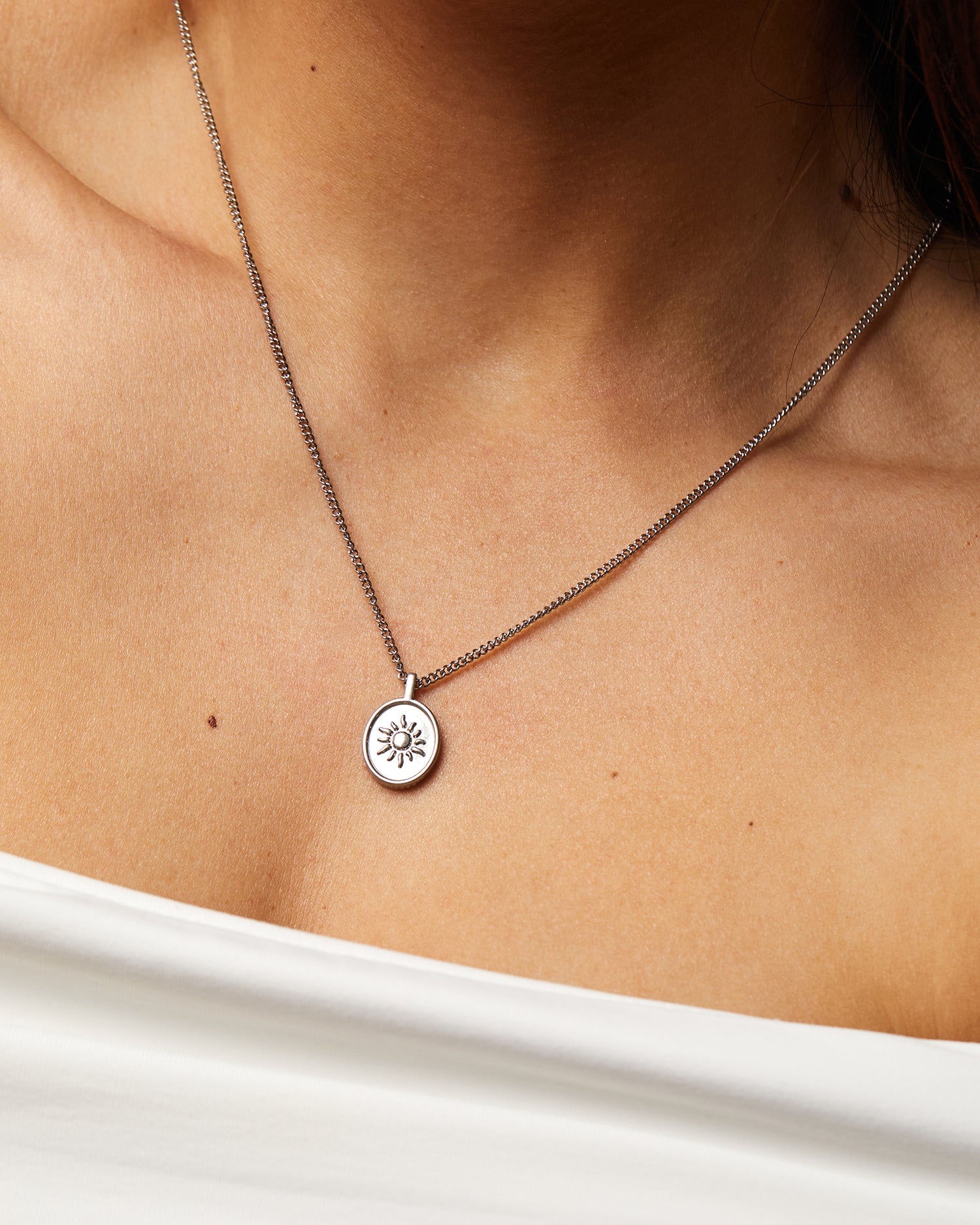 Collar Sentinel® en acero con medalla de sol sobre el escote