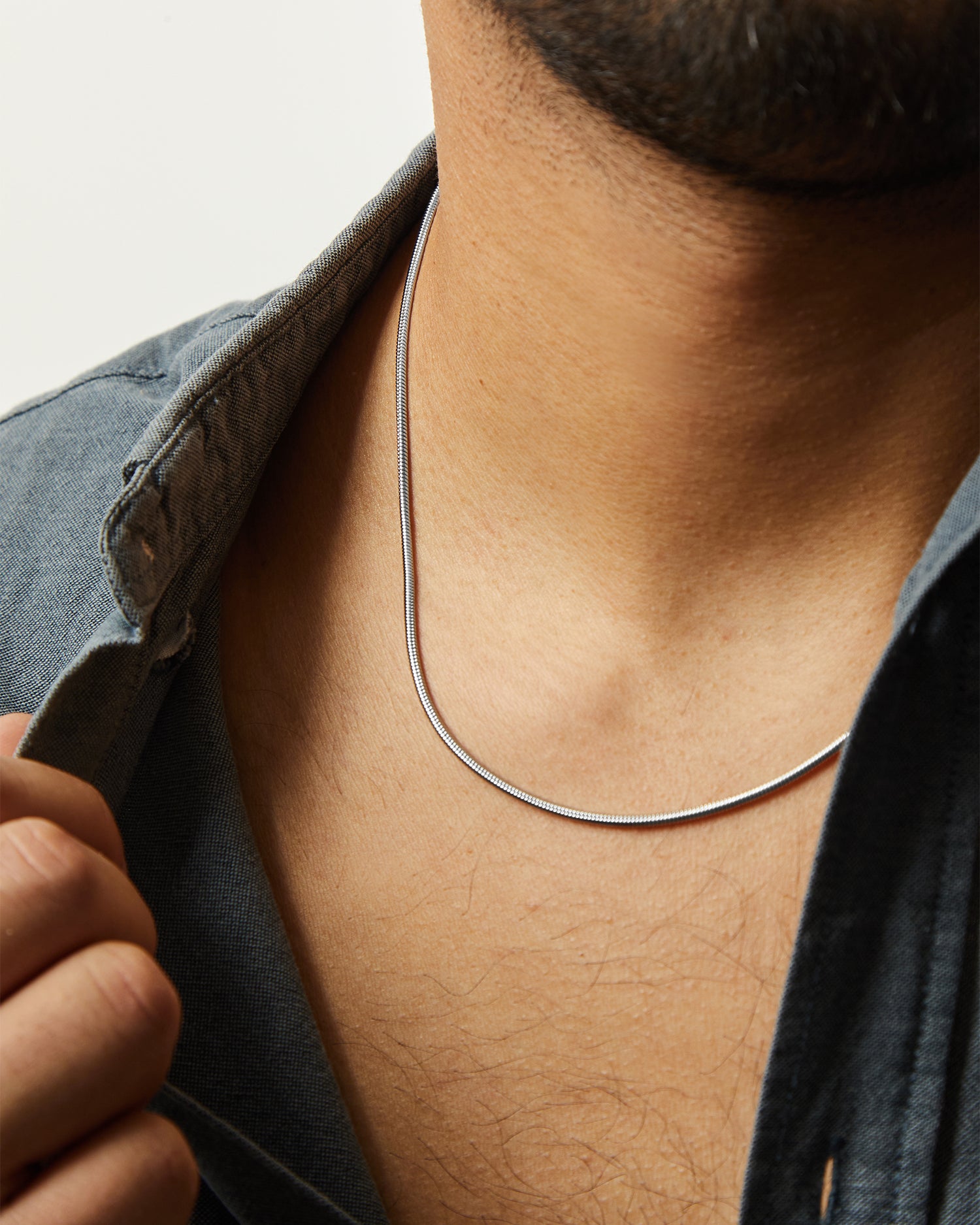Collar Boa® en acero de eslabón tipo serpiente llevado al cuello con camisa vaquera
