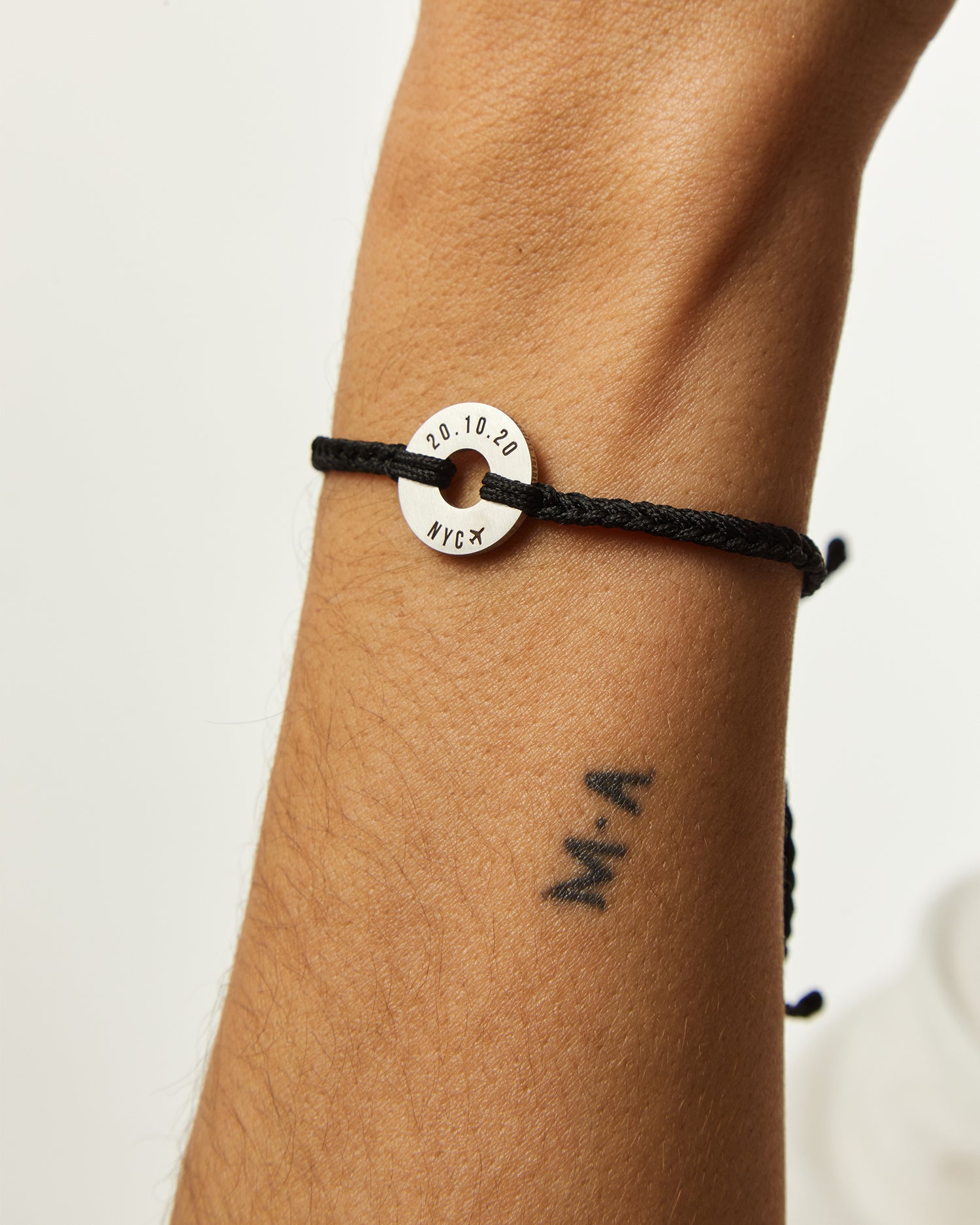 Pulsera MyWord® negra con anilla grabada en la muñeca, vista de perfil