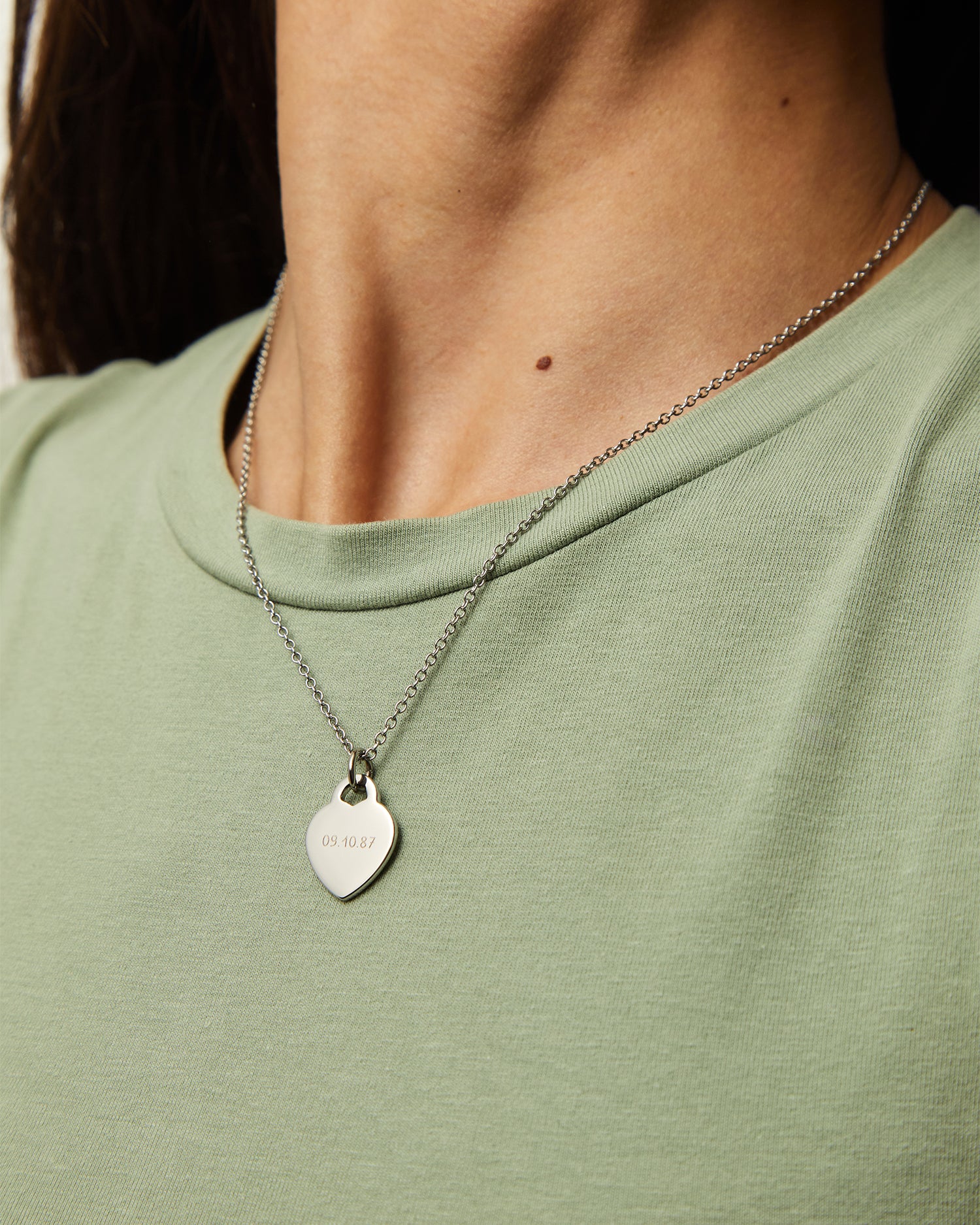 Collar Evora en acero con Colgante Corazón® sobre una camiseta verde