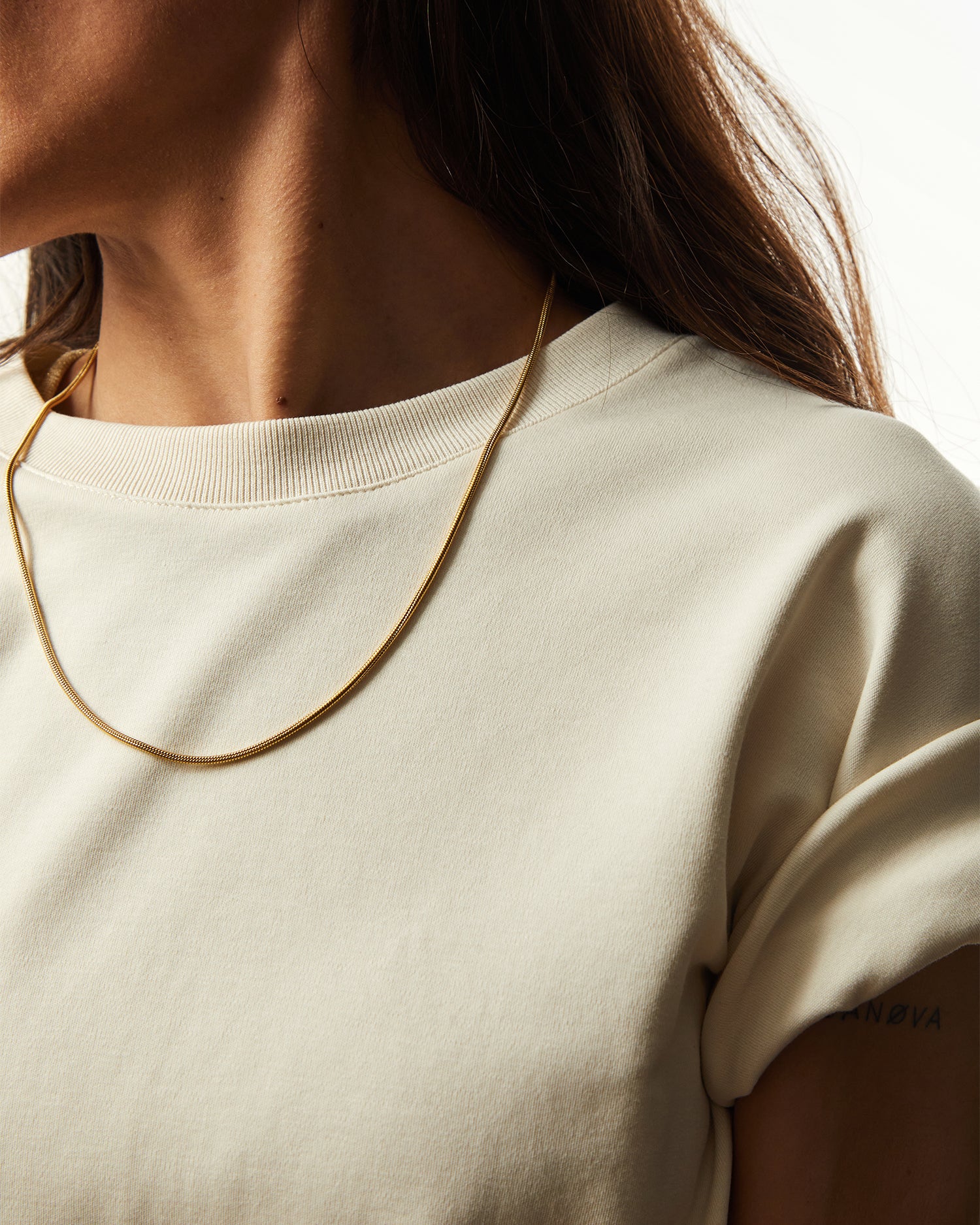 Collar Boa® dorado llevado sobre una camiseta clara, vista lateral