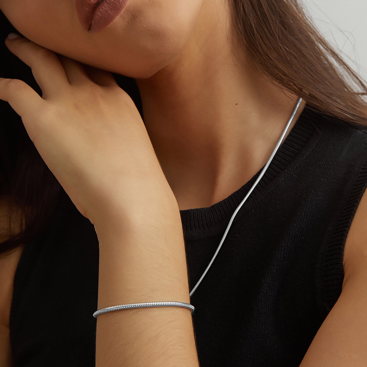 Collar y pulsera Boa® en acero llevados juntos, con la mano en el cuello