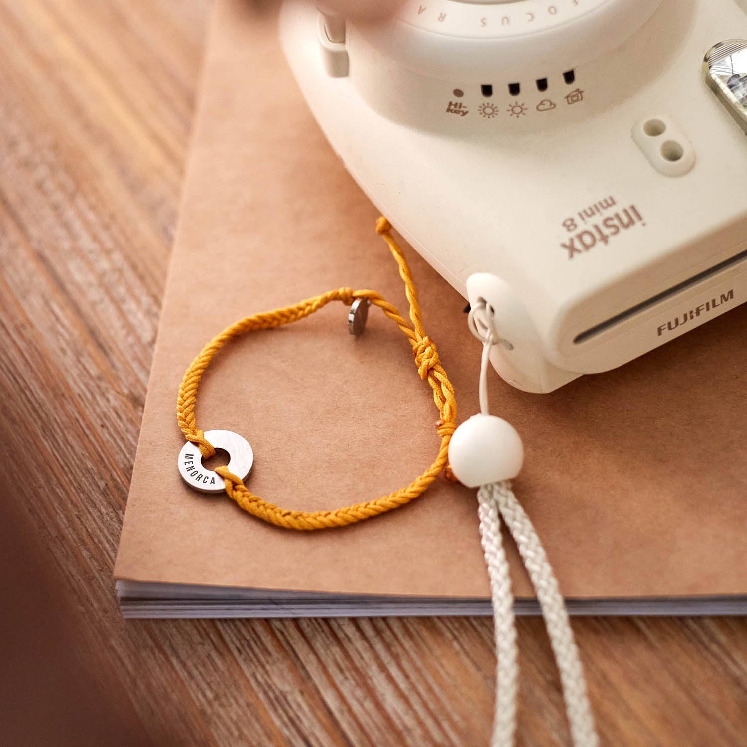 Pulsera MyWord® naranja junto a una cámara instantánea sobre un cuaderno