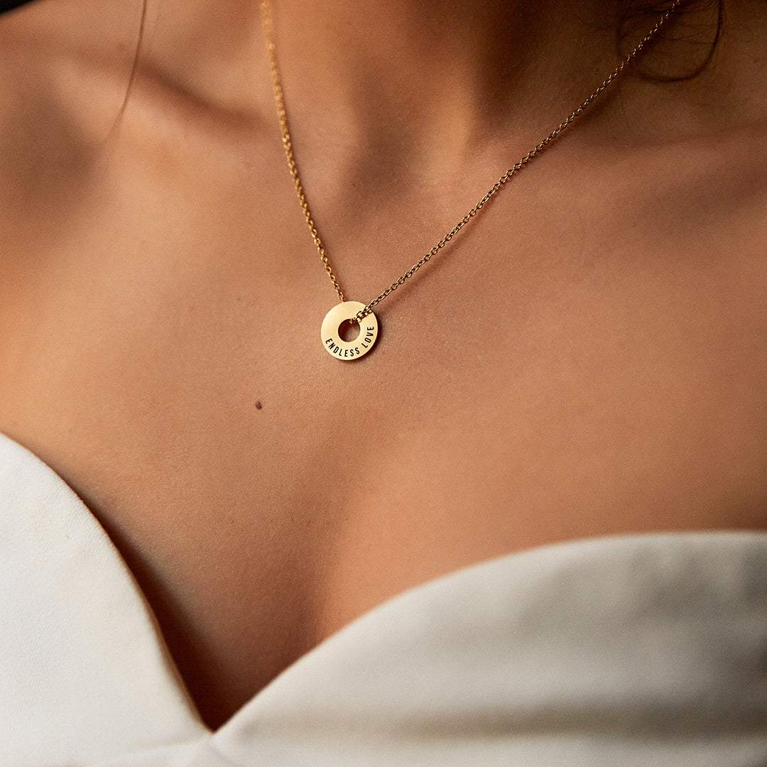 Collar Evora dorado con Anilla® grabada sobre una camisa blanca