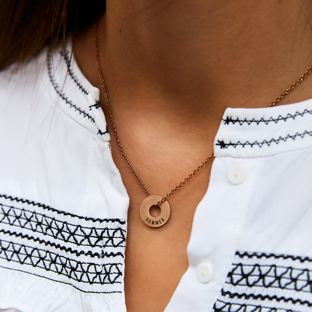 Collar Evora en oro rosa con Anilla® grabada sobre una blusa blanca bordada