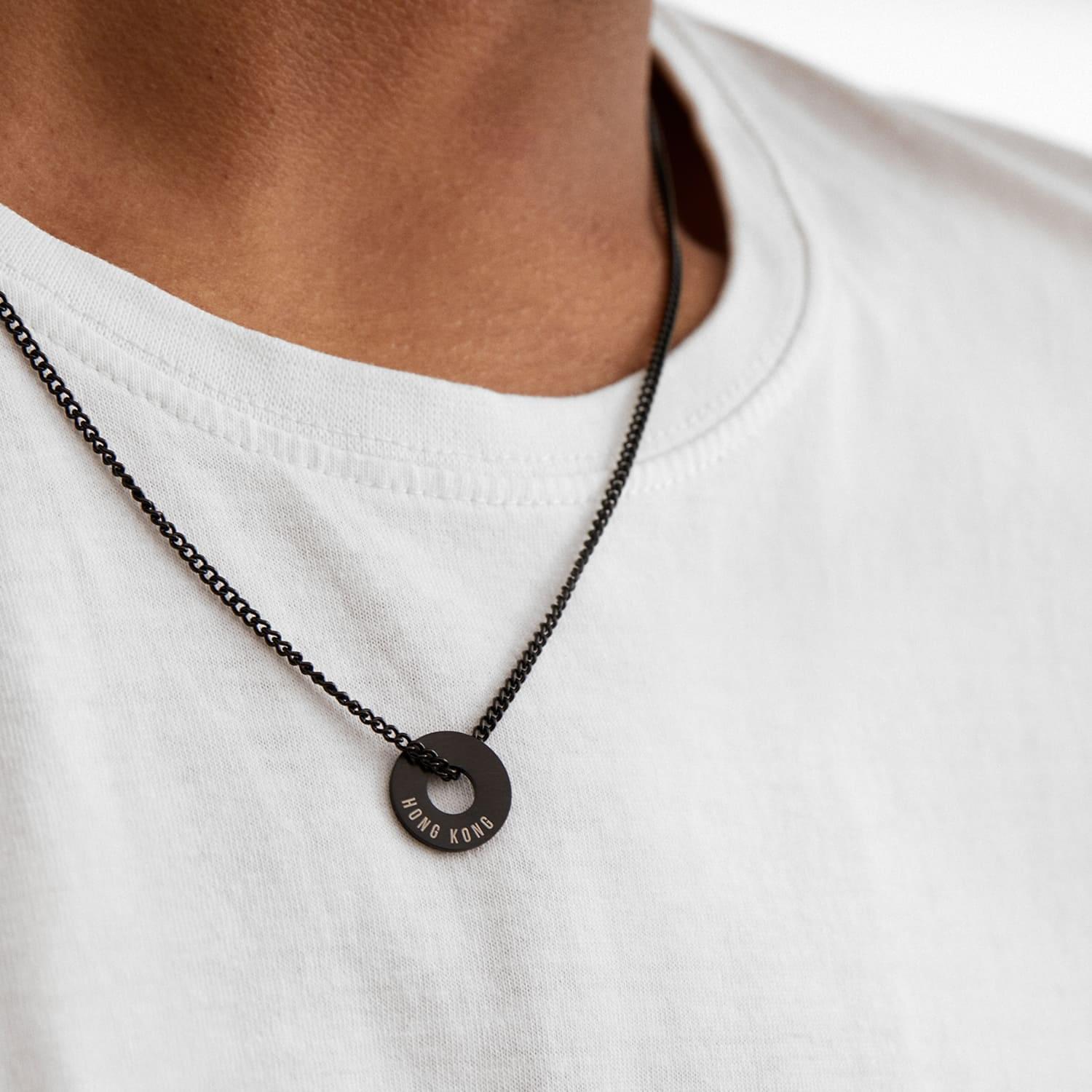 Anilla® negra montada en una cadena, llevada sobre una camiseta blanca