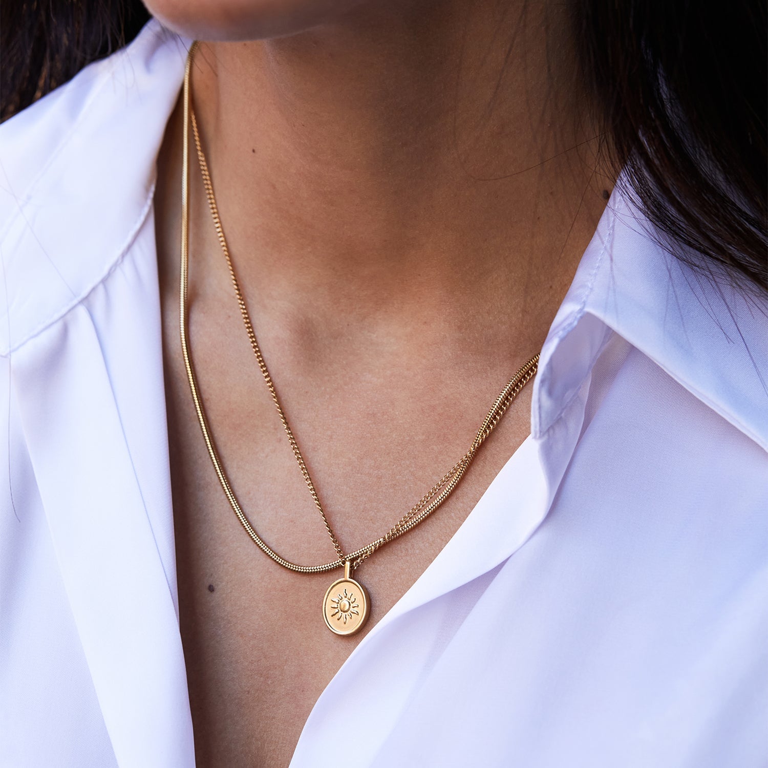 Collar Boa® dorado combinado con la medalla Namib® sobre una camisa blanca