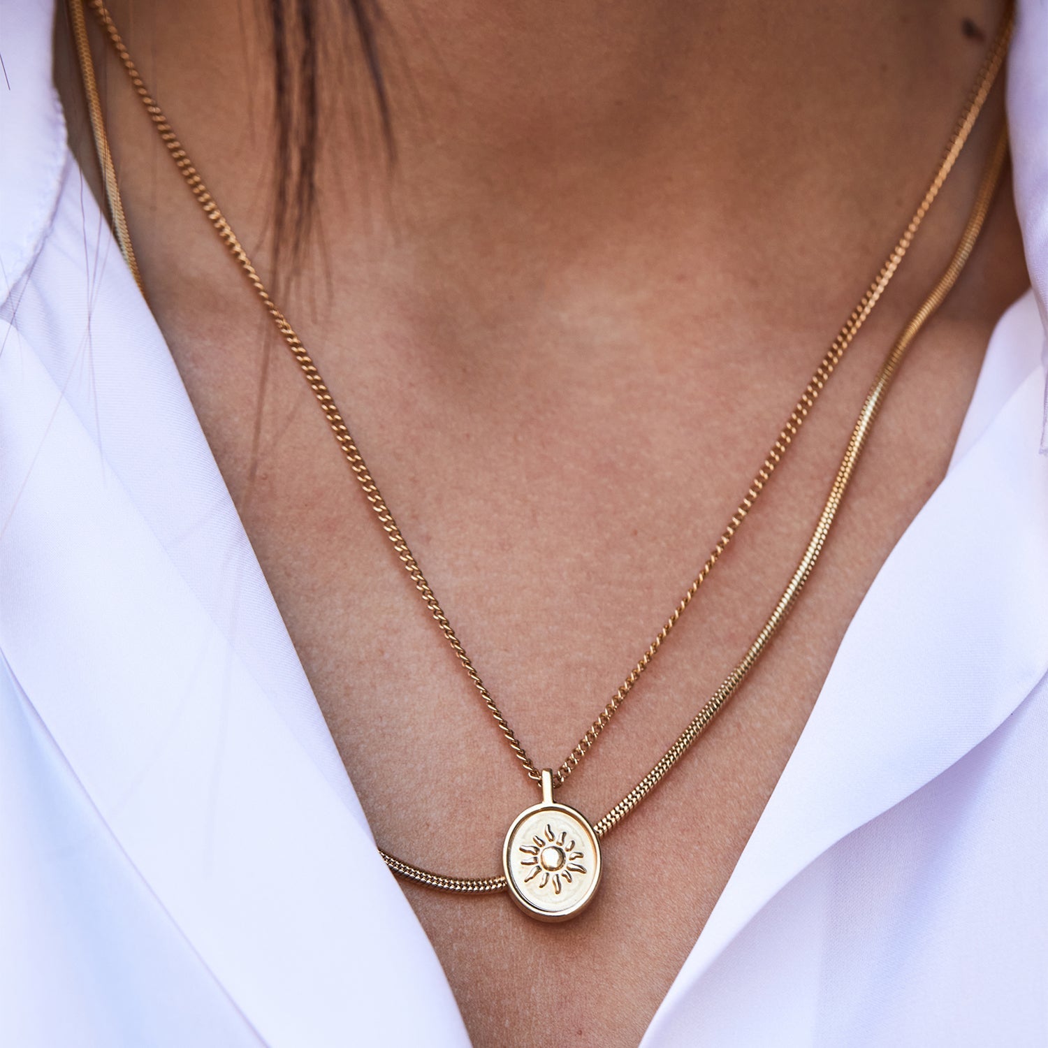 Collar Boa® dorado en capas con la medalla Sentinel® sobre una camisa blanca