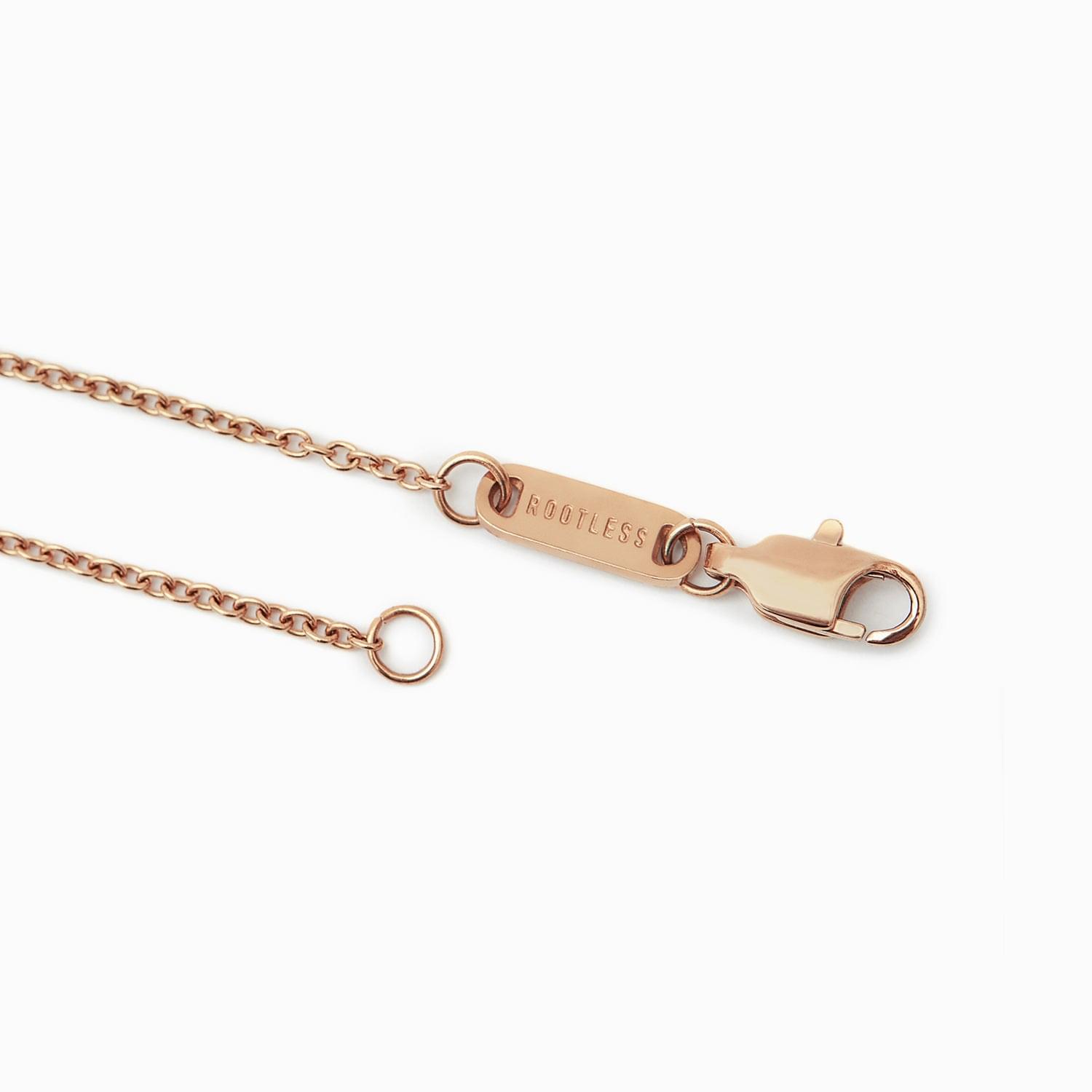 Detalle del mosquetón y la chapa ROOTLESS del collar Evora en oro rosa