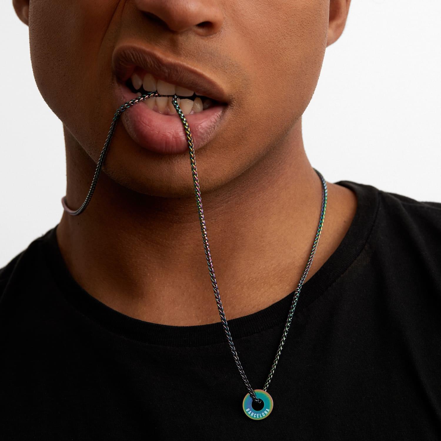 Anilla® arcoíris en cadena sostenida entre los labios, sobre camiseta negra