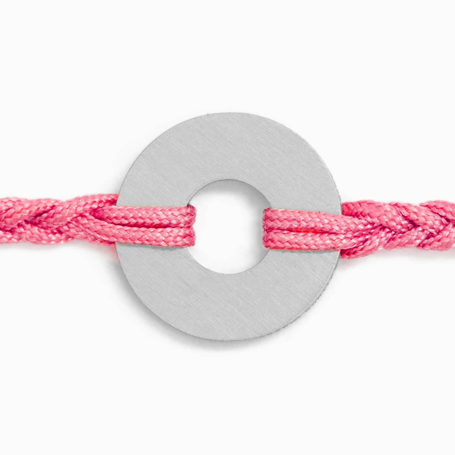 Detalle macro de la anilla en acero ensartada en el cordón trenzado rosa