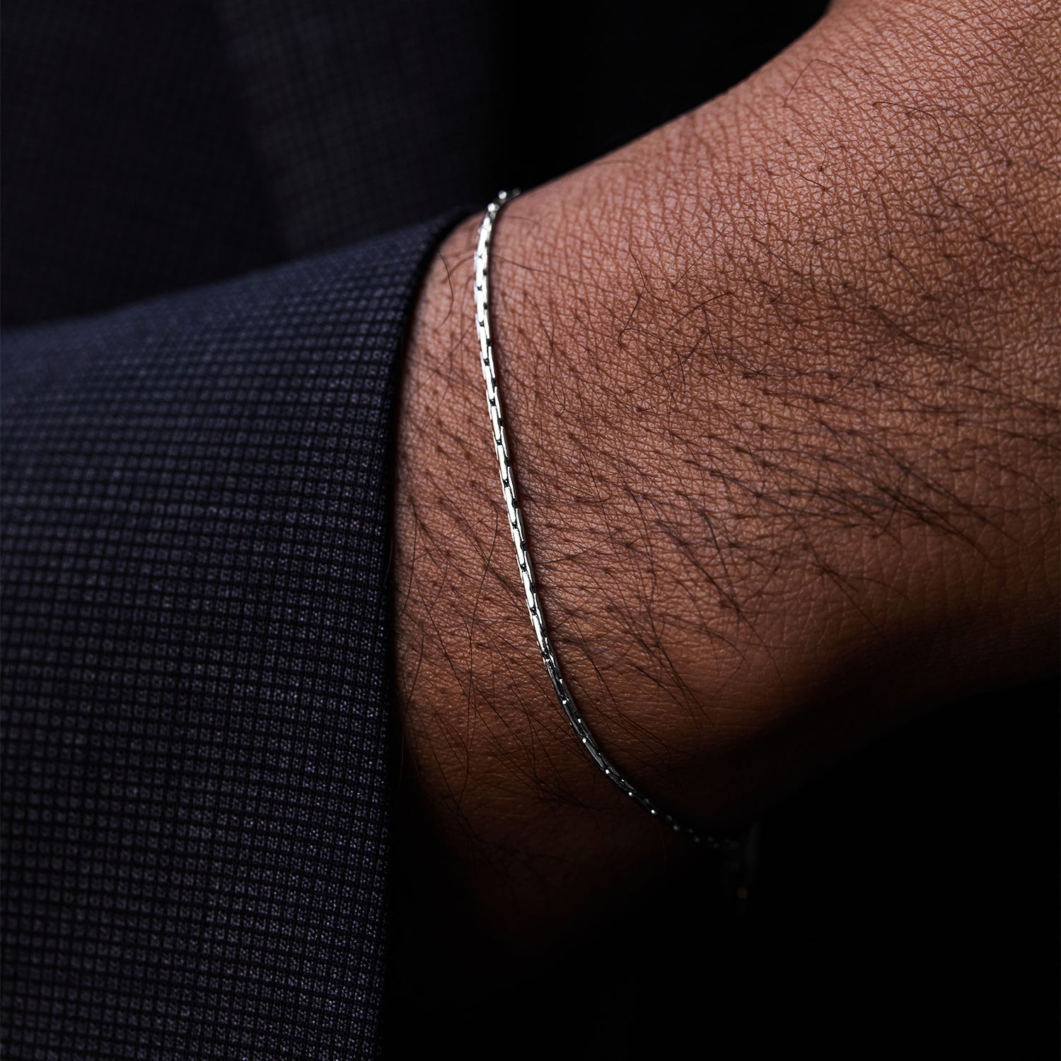 Pulsera Mamba® en acero en la muñeca asomando bajo la manga de una chaqueta