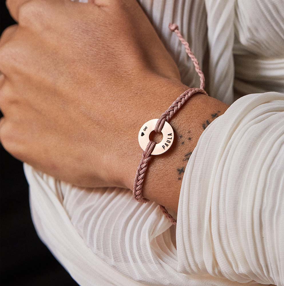 Pulsera MyWord® nude con anilla de oro rosa en la muñeca, sobre blusa blanca