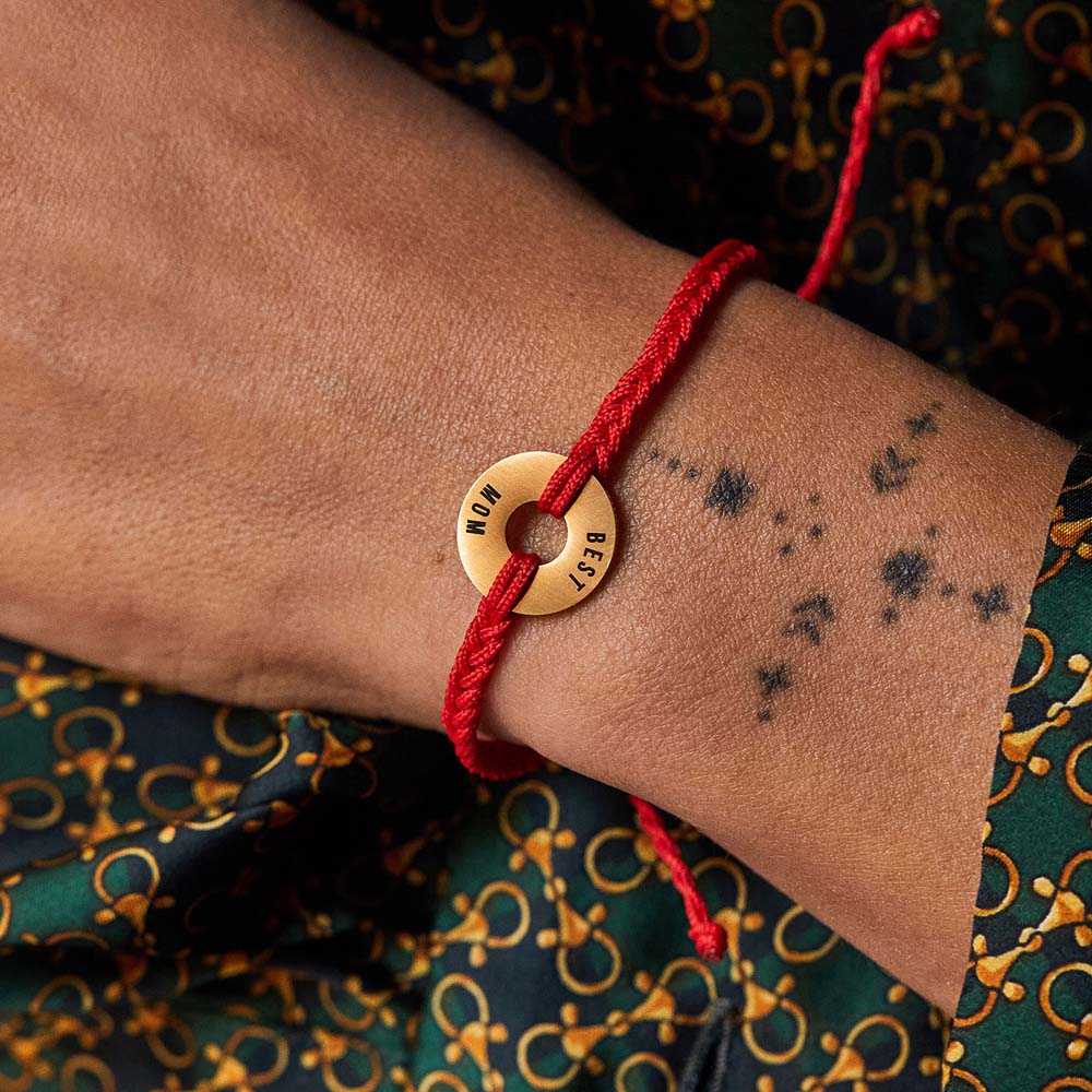 Pulsera MyWord® roja con anilla dorada grabada puesta en la muñeca