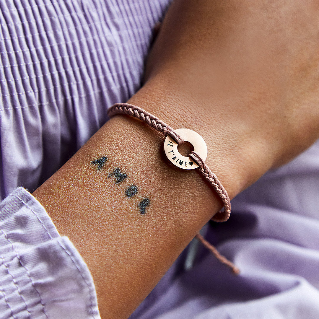 Pulsera MyWord® nude con anilla de oro rosa grabada JE T'AIME en la muñeca
