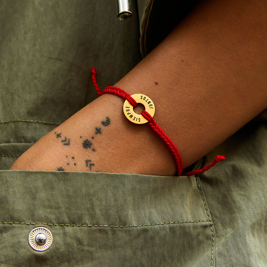 Pulsera MyWord® roja con anilla dorada llevada sobre una chaqueta caqui