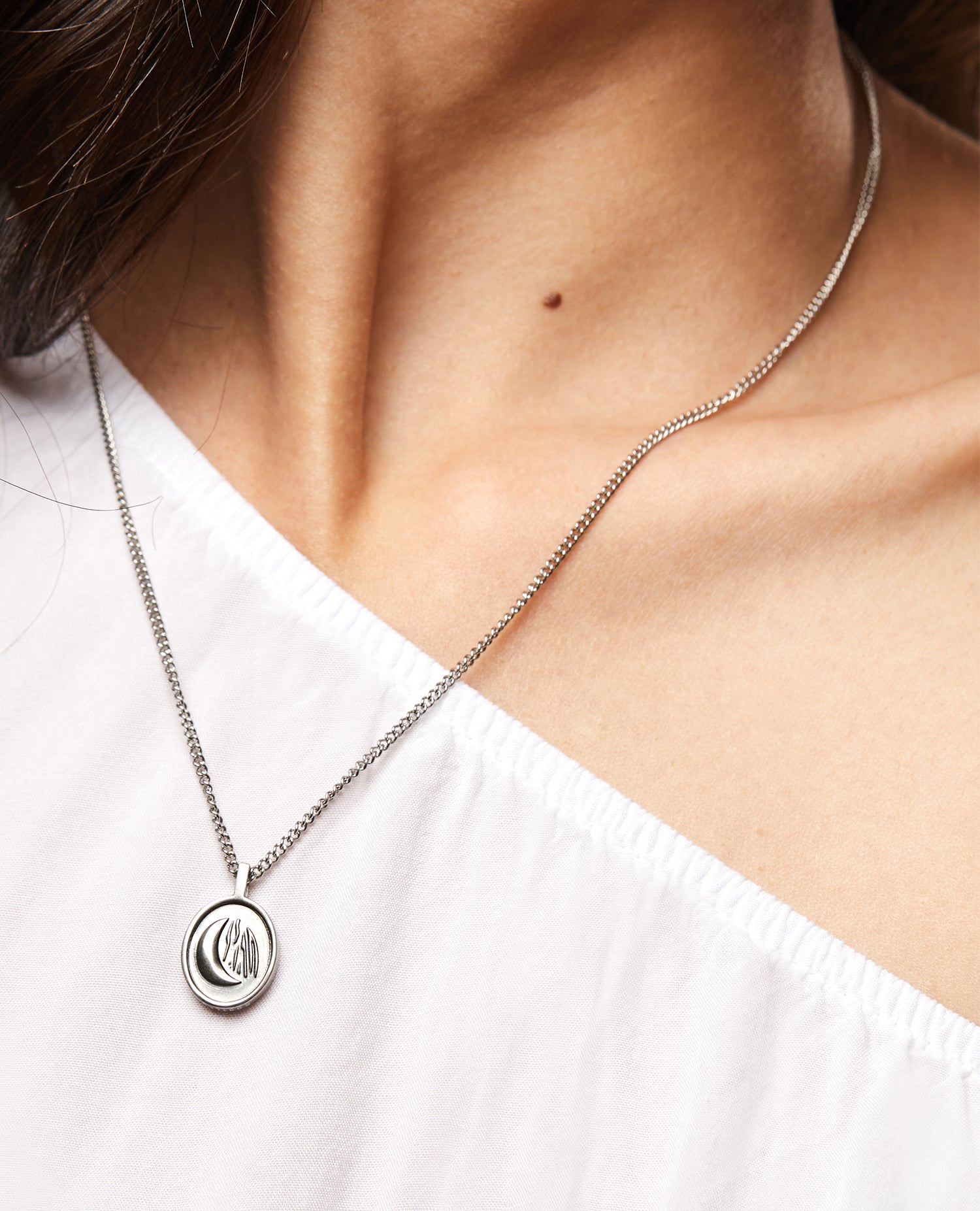 Medalla Sentinel® en acero con relieve de luna sobre una camiseta blanca