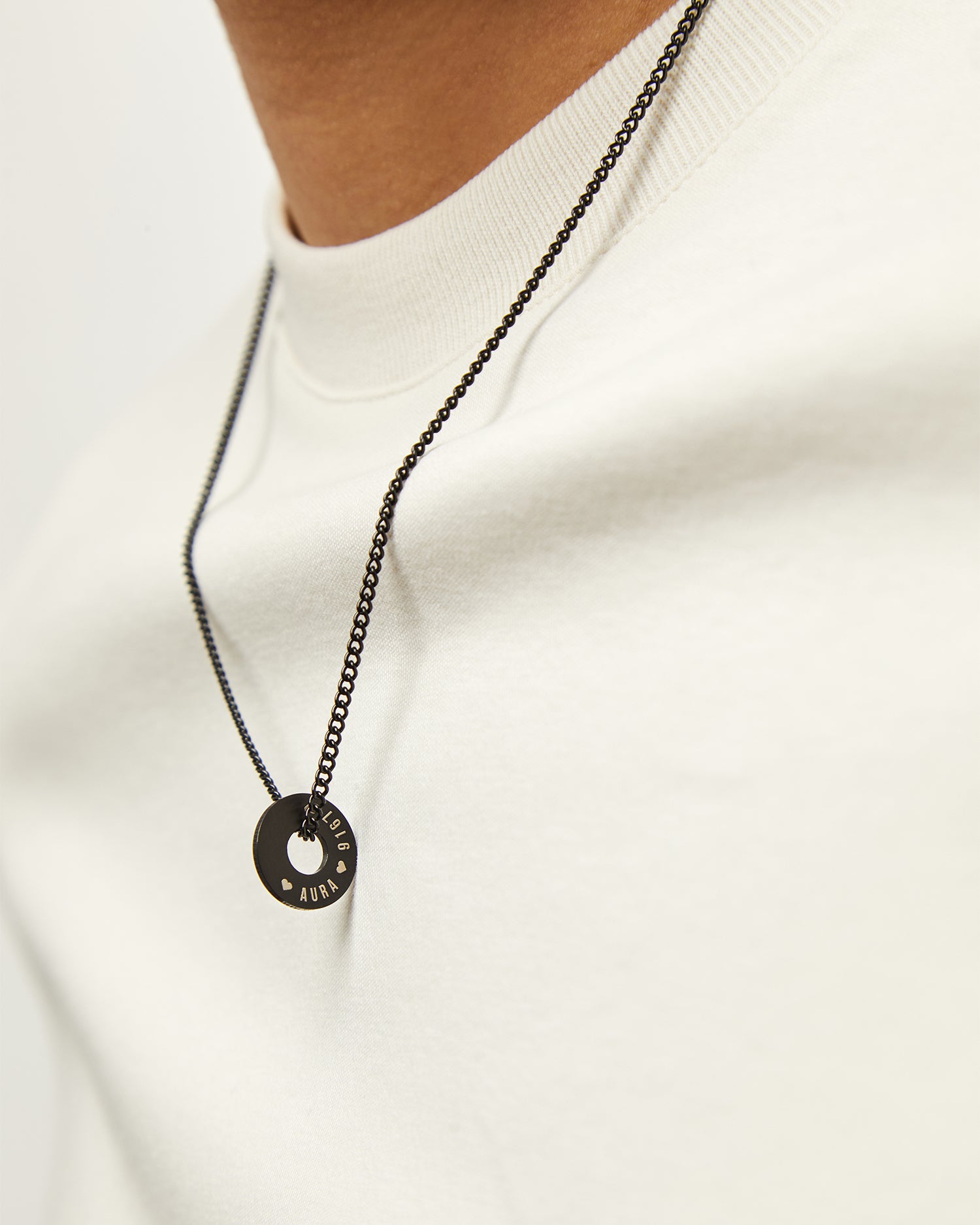 Collar Botany negro con Anilla® grabada sobre una sudadera crema