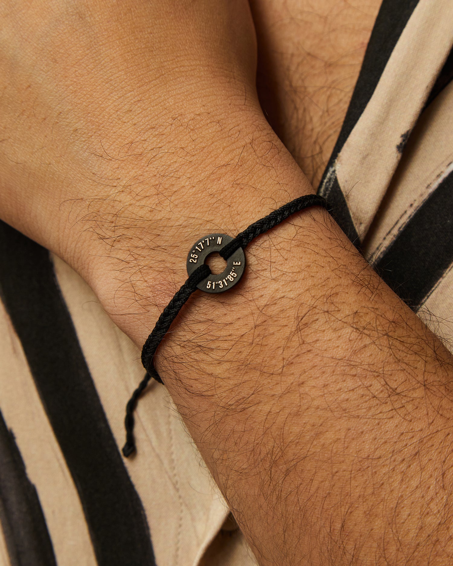 Pulsera MyWord® negra en la muñeca sobre una camisa de rayas