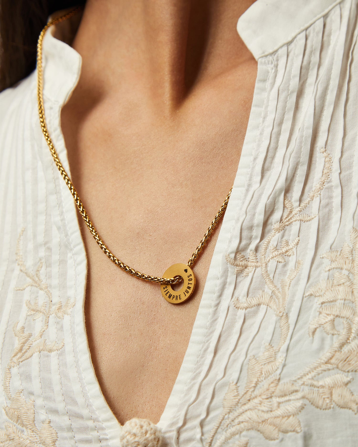 Collar Native dorado con Anilla® grabada sobre una blusa blanca bordada