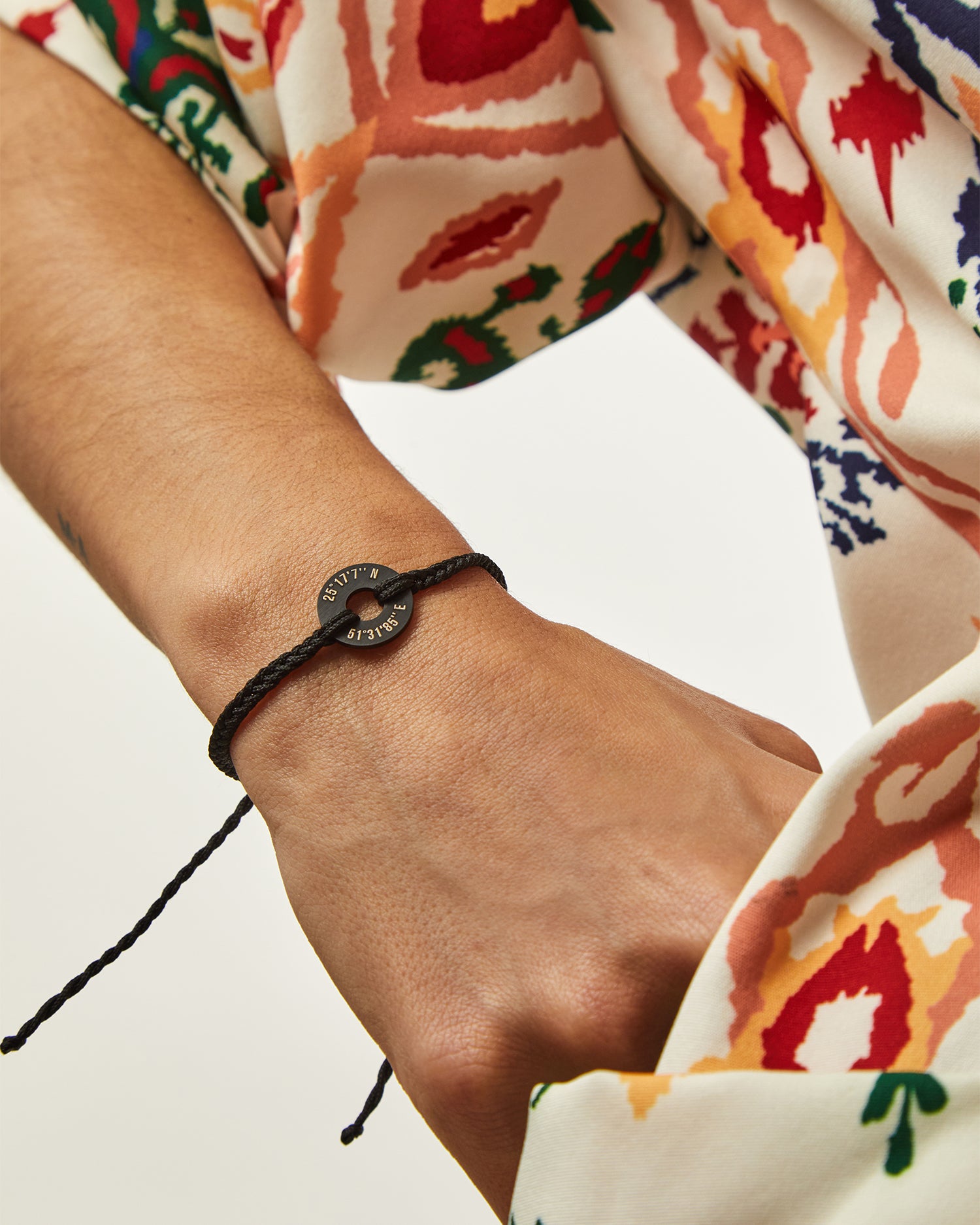 Pulsera MyWord® negra en la muñeca junto a una manga estampada