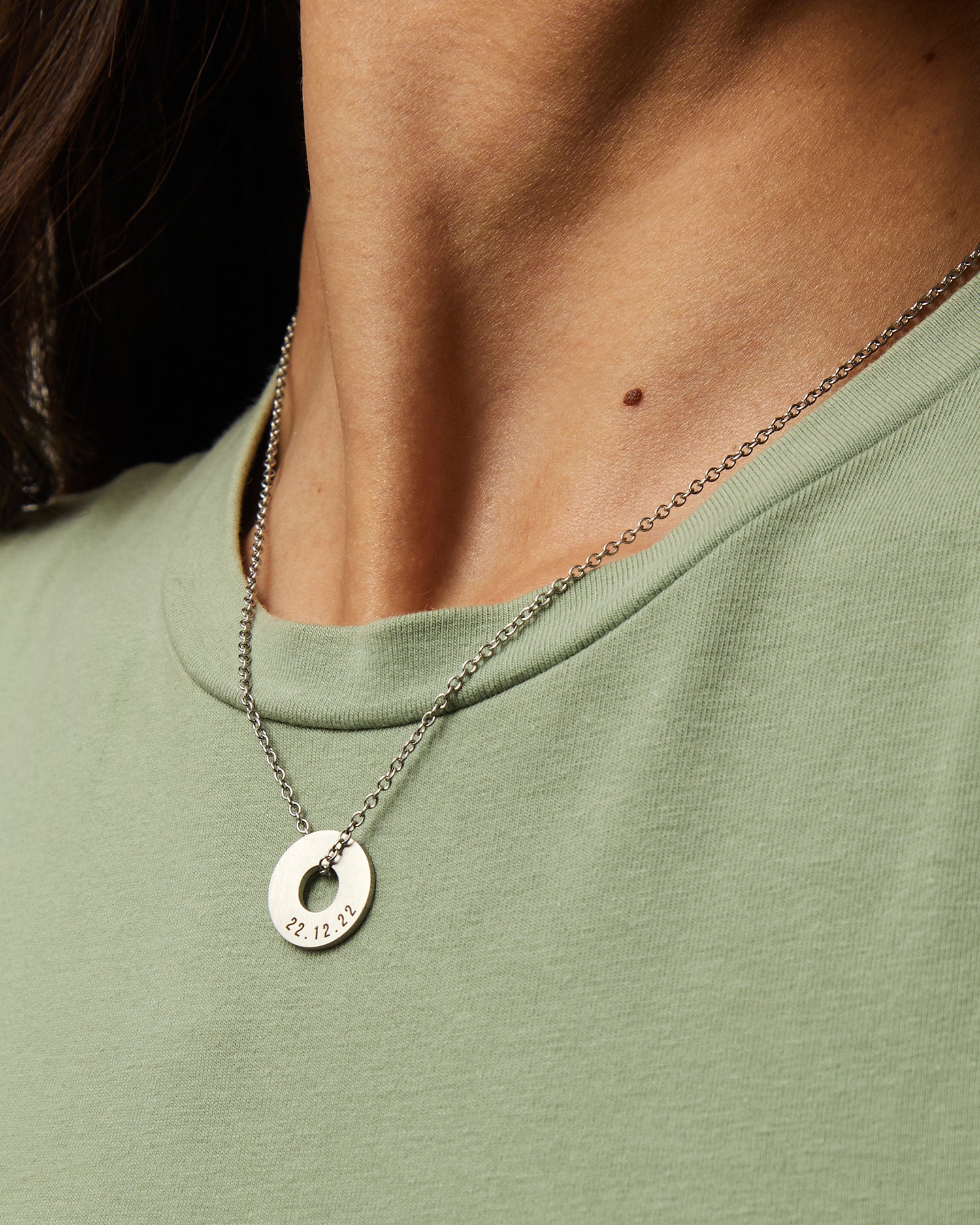 Collar Evora en acero con Anilla® grabada sobre una camiseta verde
