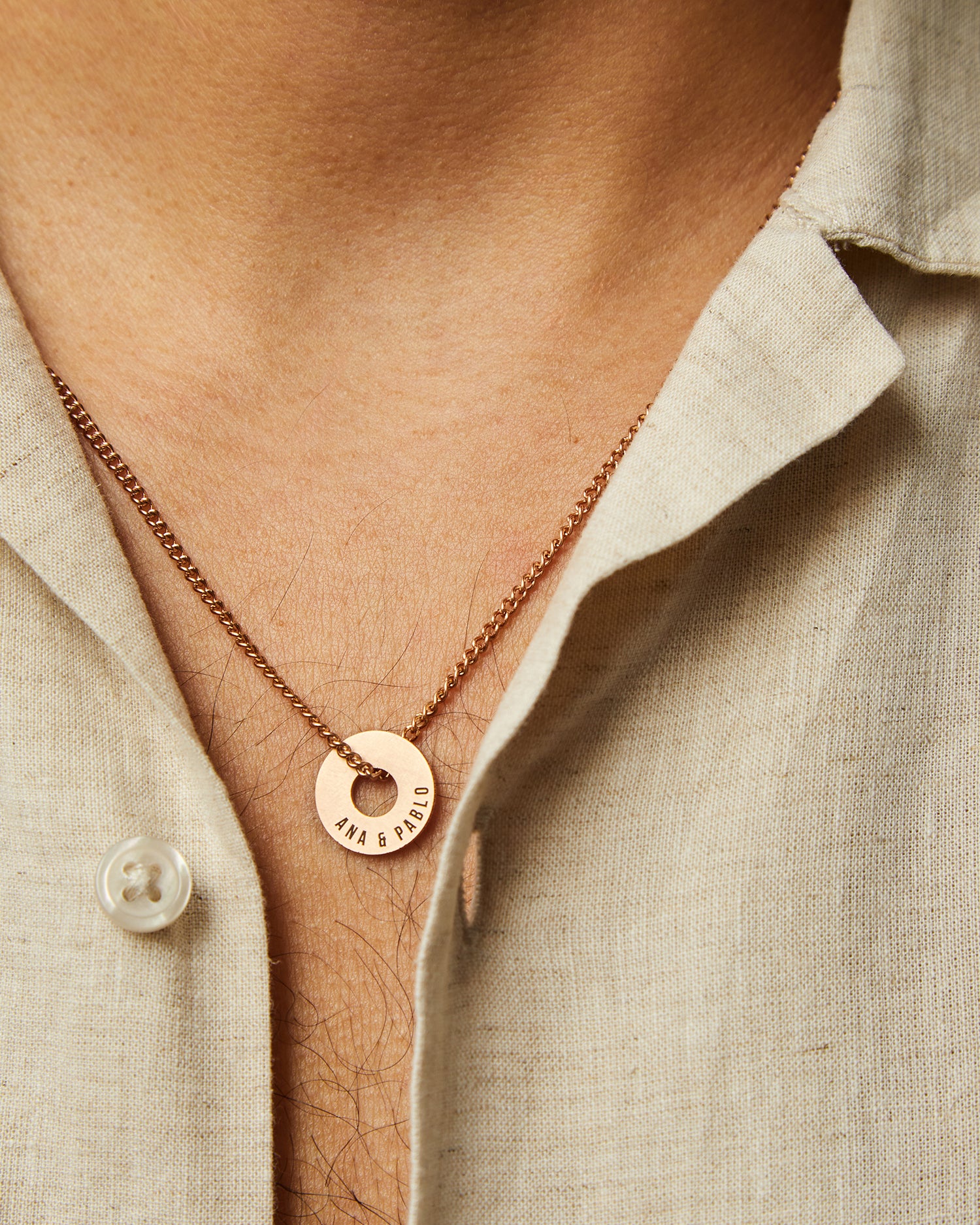 Collar Botany en oro rosa con Anilla® grabada sobre una camisa de lino