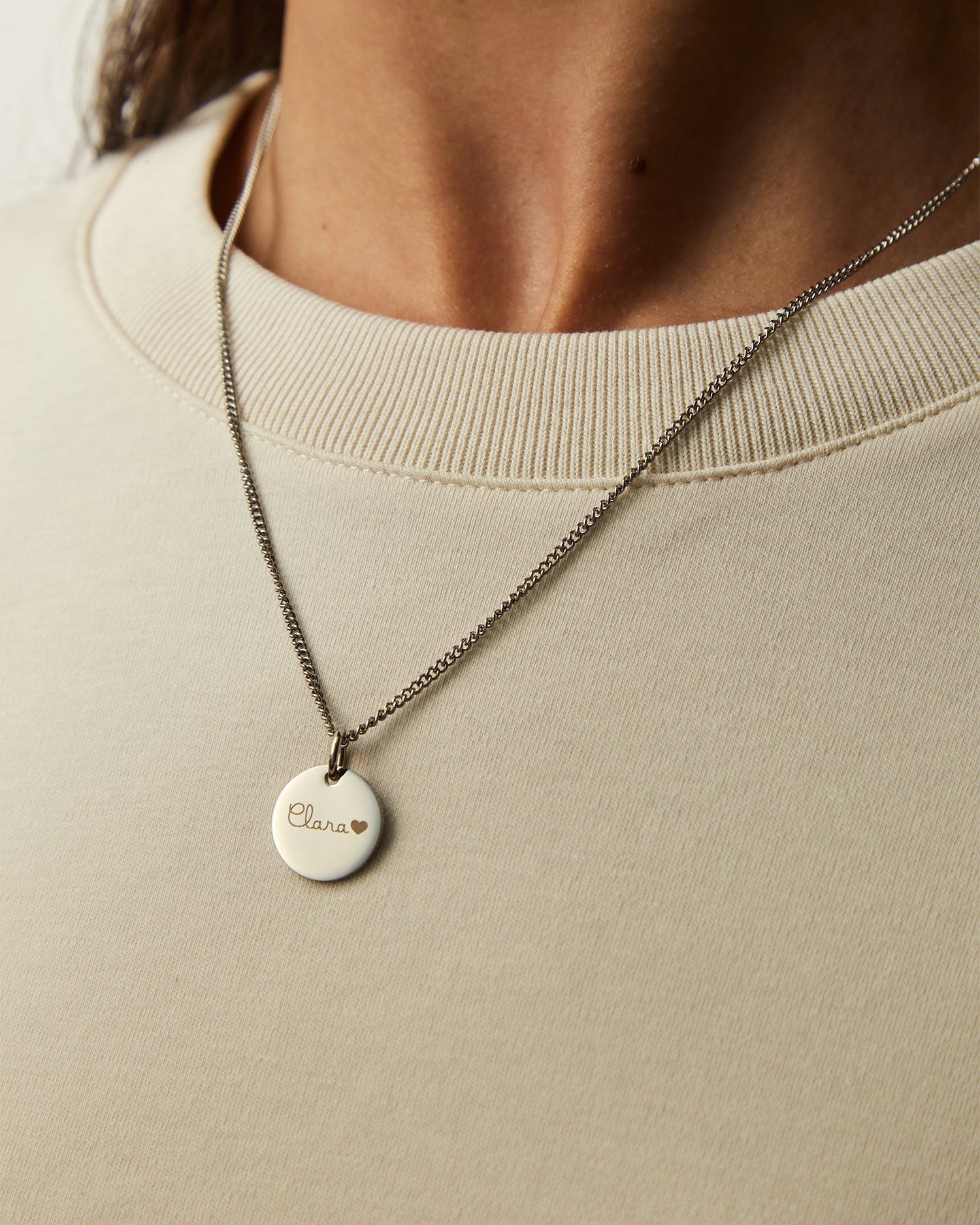 Collar Botany en acero con Colgante Circle® grabado sobre una camiseta beige