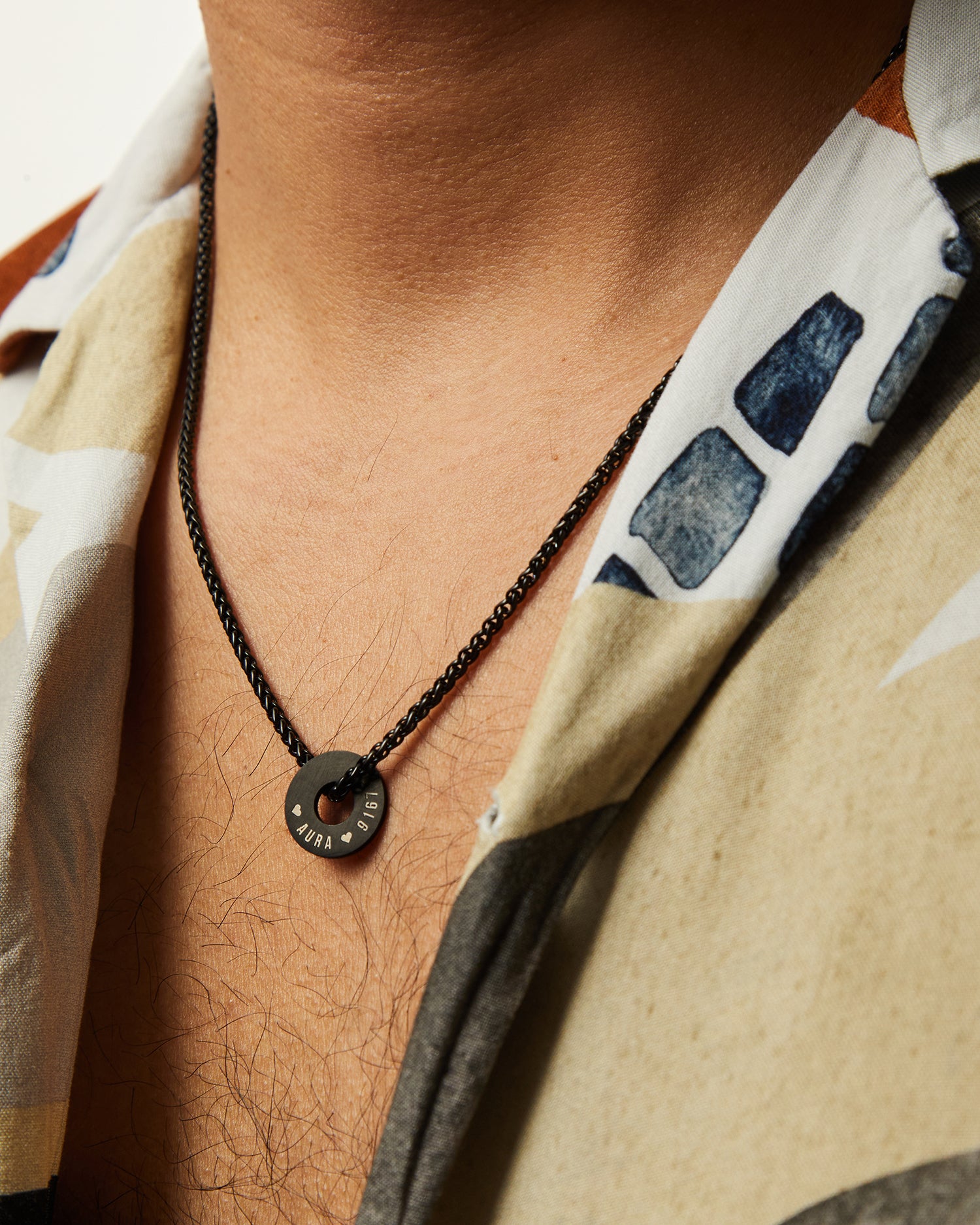 Collar Native negro con Anilla® grabada llevado con camisa estampada