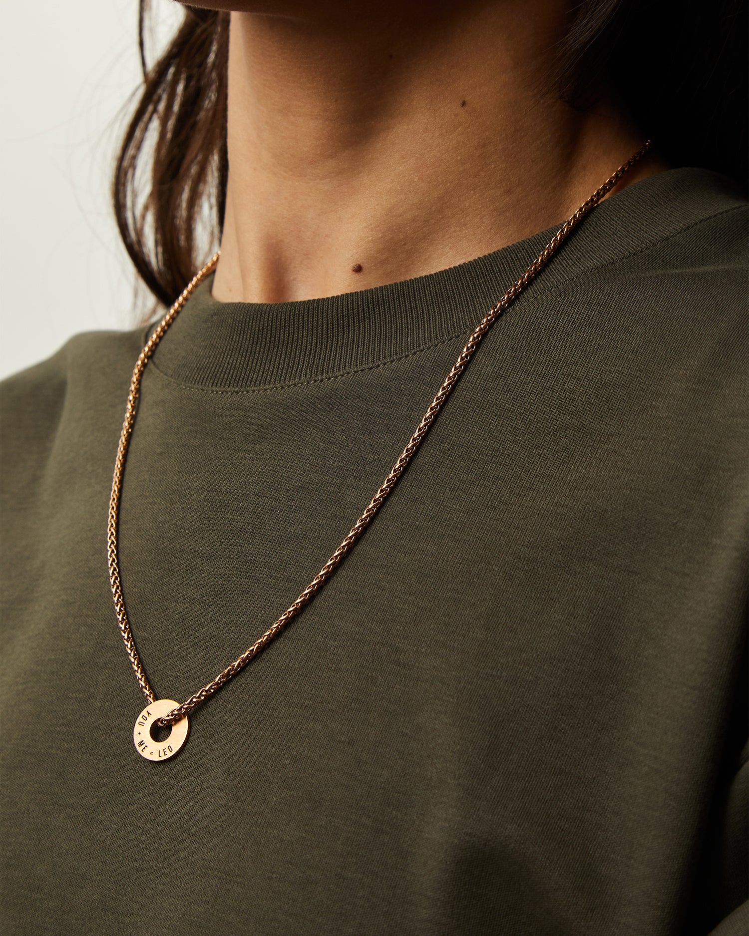Anilla® en oro rosa y cadena Native sobre una camiseta verde