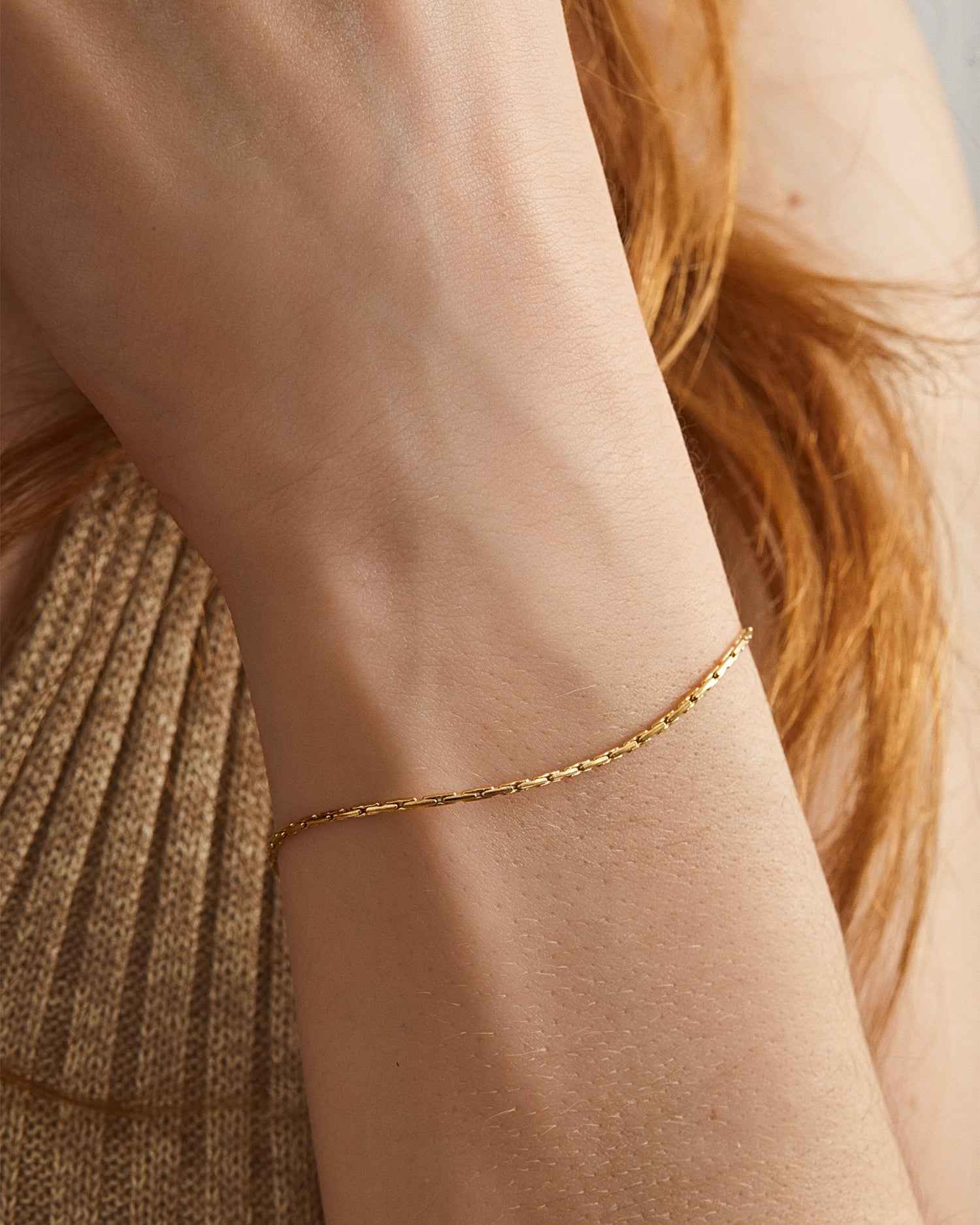 Pulsera Mamba® dorada puesta en la muñeca sobre un jersey de punto