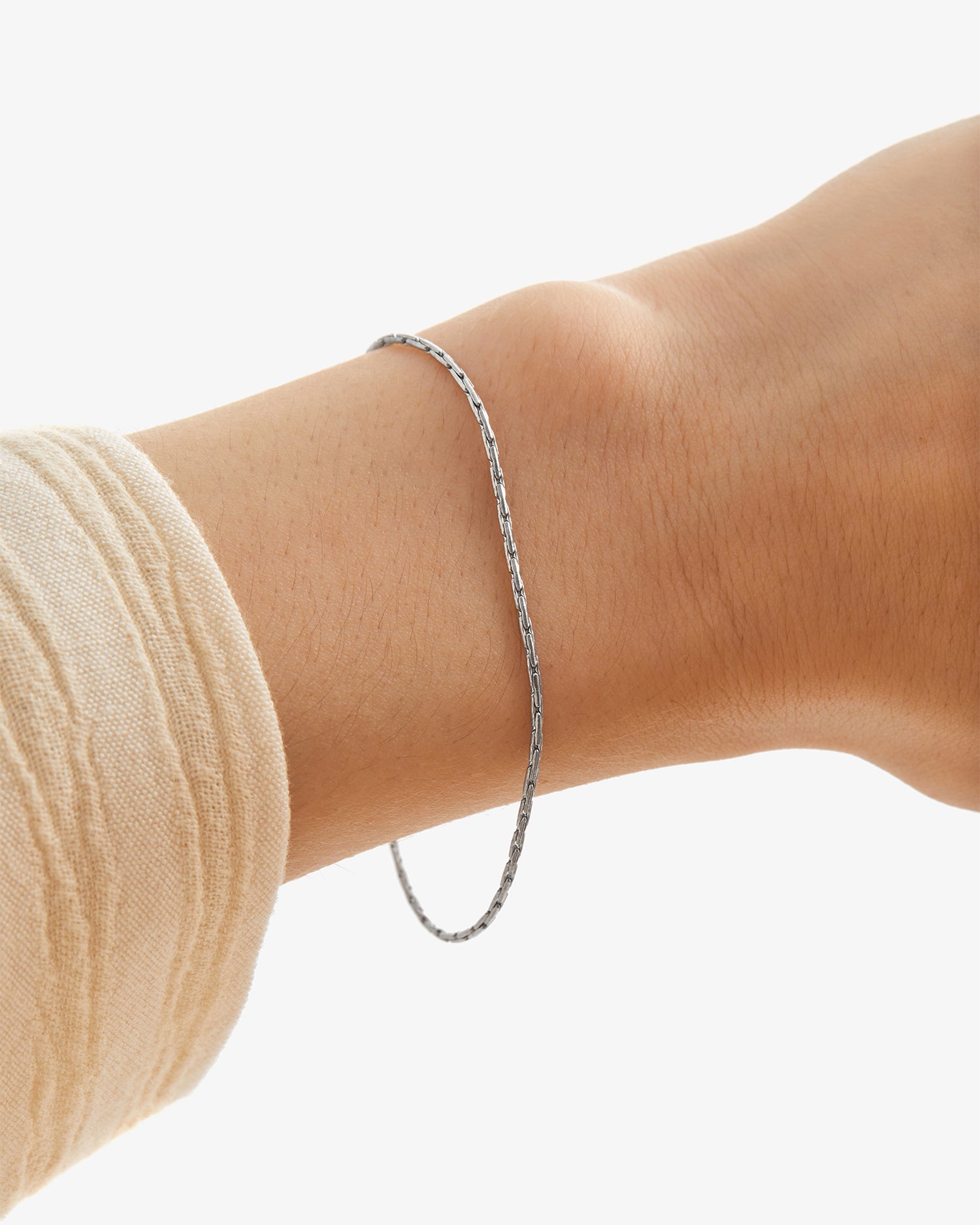 Pulsera Mamba® en acero puesta en la muñeca junto a un puño de punto