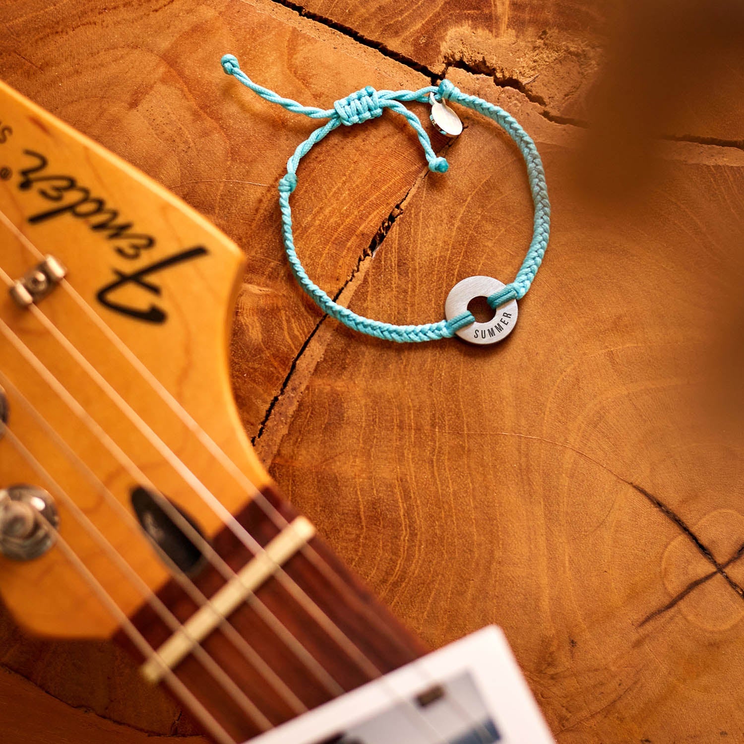 Pulsera MyWord® azul Formentera apoyada sobre una guitarra de madera