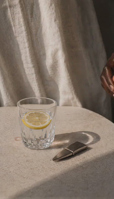 Pulsera Boa de plata esterlina maciza 925 junto a un vaso de agua con limón en ambiente mediterráneo