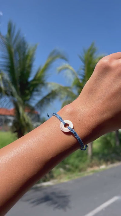 Pulsera Silver Baby Blue de ROOTLESS en la muñeca, fondo de palmeras en Bali